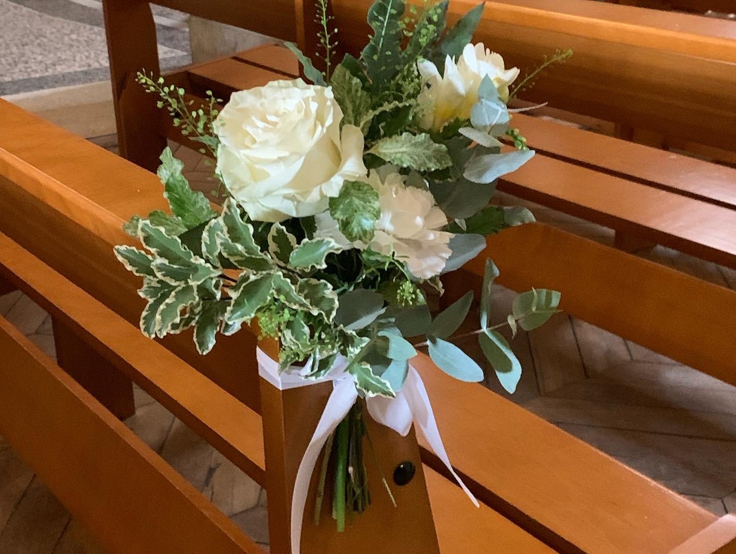 Bouquet de fleurs blanches accroché à un banc pour une cérémonie